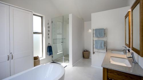 a white bathroom with a tub and a sink at Willow Beach House - with backup power in Noordhoek