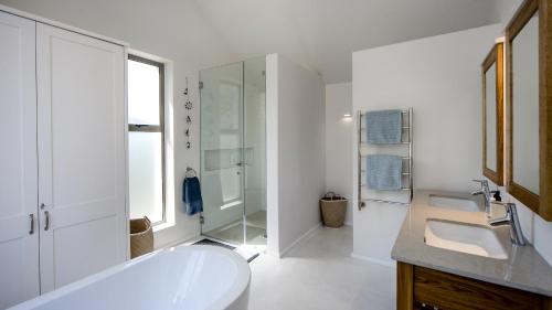 Baño blanco con bañera y lavamanos en Willow Beach House - with backup power, en Noordhoek