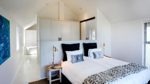 a bedroom with a large white bed with blue pillows at Willow Beach House - with backup power in Noordhoek