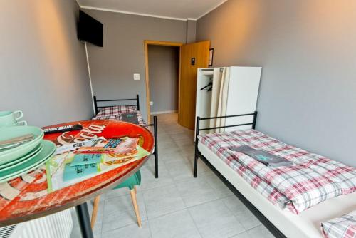 een kamer met 2 bedden, een tafel en een koelkast bij miniHostel Żary in Żary