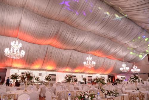 a large banquet hall with white tables and chandeliers at Pearl Continental Hotel, Karachi in Karachi