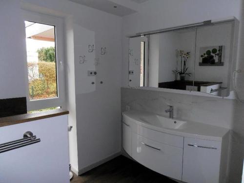 a white bathroom with a sink and a mirror at Moderne-Ferienwohnung-in-ruhiger-Lage in Quickborn