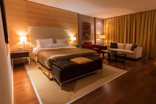 a hotel room with a large bed and a chair at Hotel Grand Swiss in Erbil