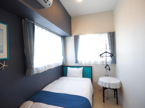 a small bedroom with a bed and a window at Guest House Orihime in Ishigaki Island