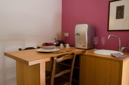 una cucina con tavolo in legno, lavandino e dispenser di asciugamani di carta di Dimora La Rosa Barocca a Palazzolo Acreide