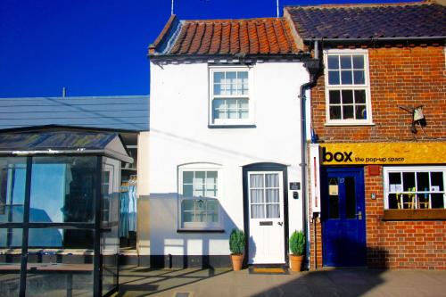 a white building with a blue door on a street at Seaside Fisherman Cottage Southwold in Southwold