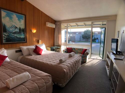 クライストチャーチにあるTui Lodge Motelのベッド2台とテレビが備わるホテルルームです。