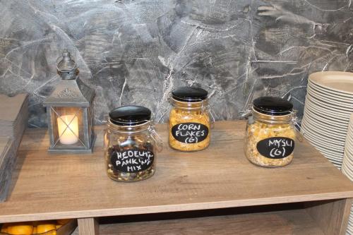 tre barattoli di sottaceti su un tavolo di legno con una candela di Hotelli Kampeli a Veteli