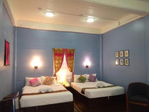 two beds in a room with blue walls at Thaweesuk Heritage Homestay in Phangnga