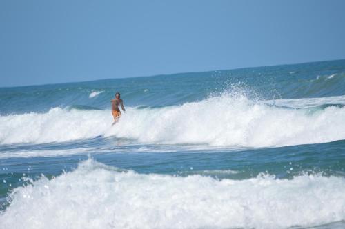 a man riding a wave on a surfboard in the ocean at Finca Valeria Treehouses Glamping in Cocles