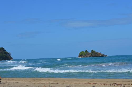 a person walking on a beach near the ocean at Finca Valeria Treehouses Glamping in Cocles