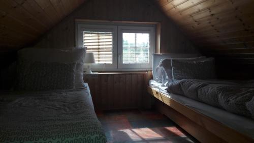 a attic room with two beds and a window at Chata v Jizerských Horách in Liberec