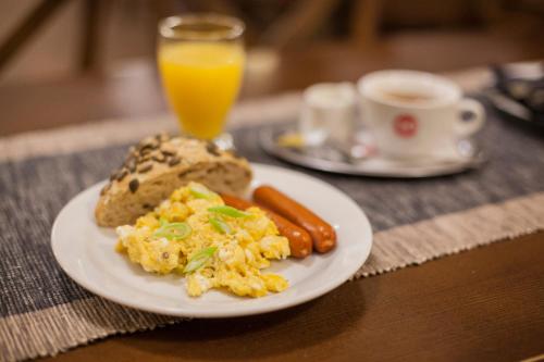 a plate of food with eggs and bread and a glass of orange juice at Penzion Černej pták in Jindřichŭv Hradec