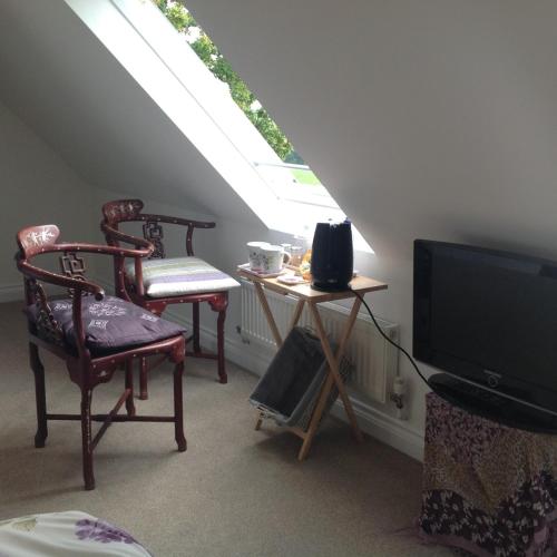 a living room with two chairs and a tv at East Hillerton House in Crediton