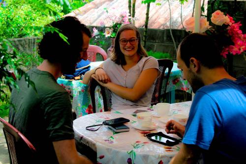 una mujer sentada en una mesa con dos hombres en J hostel kandy, en Kandy