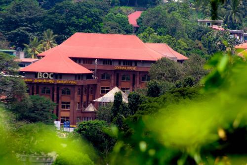 ein großes Gebäude mit rotem Dach in einem Wald in der Unterkunft J hostel kandy in Kandy