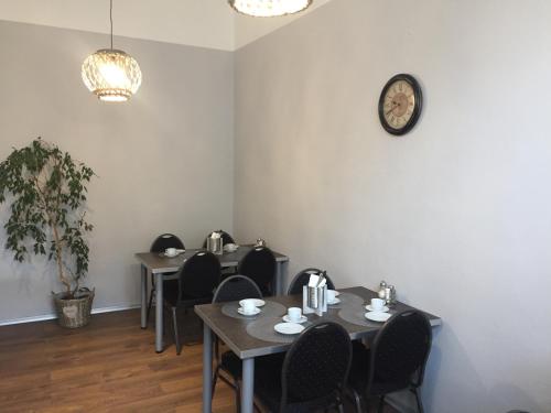 a dining room with tables and chairs and a clock on the wall at Penzion Ema B&B in Prostějov