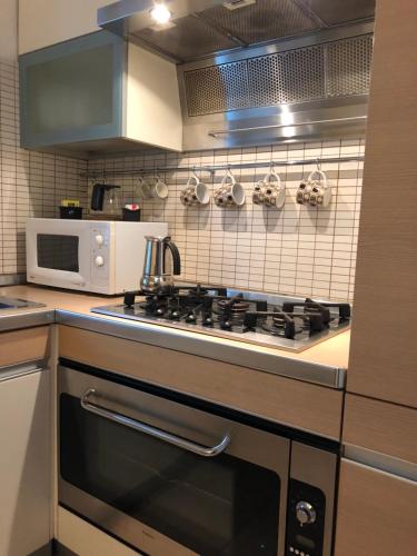 a kitchen with a stove and a microwave at La Porta Nel Giardino in Asti