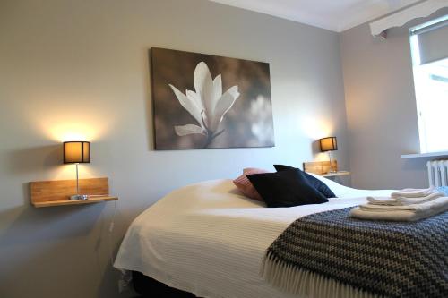 Reynisstaðir في كيفلافيك: غرفة نوم مع سرير مع لوحة زهرة بيضاء على الحائط