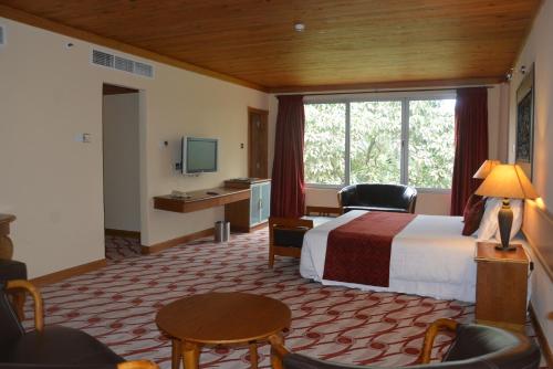カンパラにあるGolf Course Hotelのベッドと大きな窓が備わるホテルルームです。