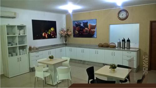 a kitchen with two tables and white cabinets at Urbano's Hotel in Canaã dos Carajás