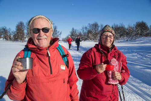 two people standing in the snow holding coffee cups at Hotell Bruksvallsliden in Bruksvallarna
