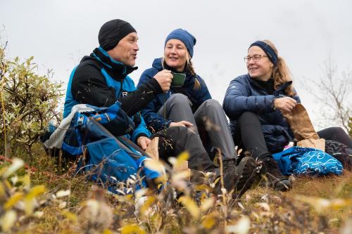 a group of three people sitting on a hill at Hotell Bruksvallsliden in Bruksvallarna