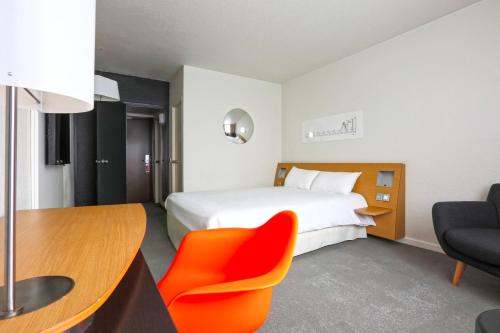 a hotel room with a bed and a desk and a chair at ibis Styles Nancy Sud in Houdemont