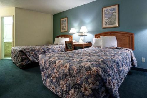 ein Hotelzimmer mit 2 Betten und einem Tisch in der Unterkunft Americas Best Value Inn Florida Turnpike & I-95 in Fort Pierce