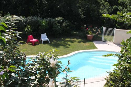 a yard with a pool with twochairs and a red chair at Vergers de la Bouligaire in Mirmande