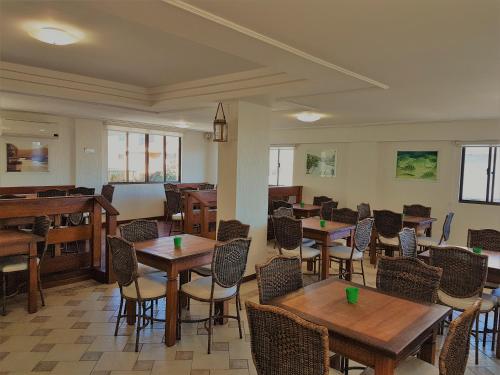 a restaurant with tables and chairs and a piano at Fragata Apart Hotel in Florianópolis