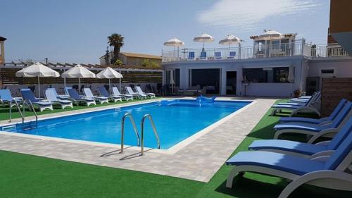 a swimming pool with lounge chairs and a house at Roda Pearl Resort in Roda