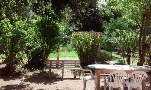 a table and chairs and a bench in a garden at Le Jardin de la Reyssouze in Gorrevod