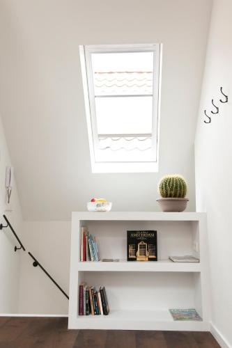 a white book shelf in a room with a window at Boutique B&B Nassau in Amsterdam