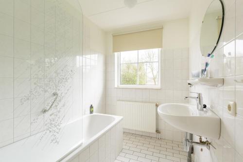 a white bathroom with a tub and a sink at Center Parcs Sandur Emmen in Emmen