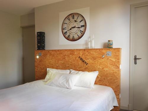 a clock on the wall above a bed with pillows at Le Jardin de la Reyssouze in Gorrevod