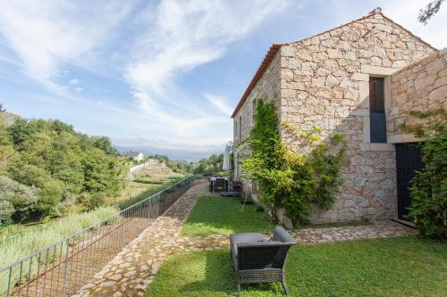 an external view of a building with chairs on the grass at Melgaço Alvarinho Houses in Melgaço