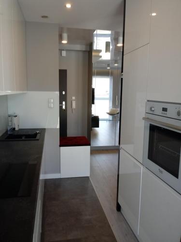 kuchnia z białymi szafkami i kuchenką w obiekcie Apartament na Złotej w Kielcach