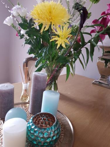 a vase with flowers and candles on a table at Evy's place in Zandvoort