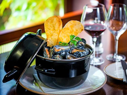 a bowl of mussels on a table with chips and wine at Kilmurry Lodge Hotel in Limerick