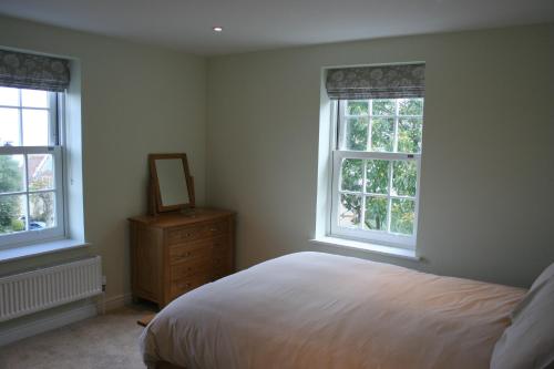 a bedroom with a bed and two windows and a dresser at Highlands Apartment 3 in Shanklin