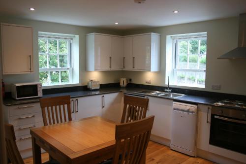 a kitchen with white cabinets and a wooden table at Highlands Apartment 3 in Shanklin