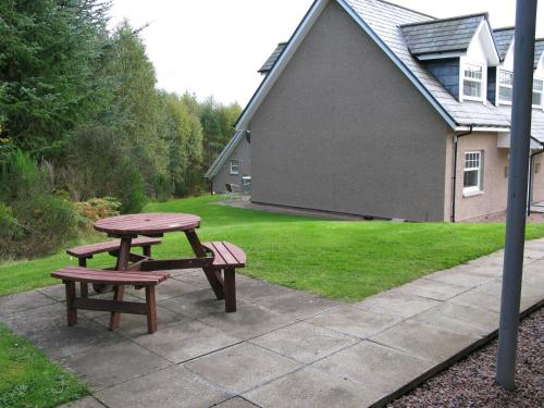 a picnic table and bench in front of a house at Apartment 20 Inchmarlo in Banchory