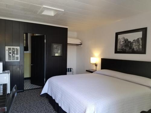um quarto com uma grande cama branca num quarto em Rocket Motel em Custer