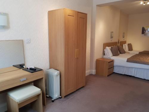 a hotel room with a bedroom with a bed and a desk at Burley Court Hotel in Bournemouth