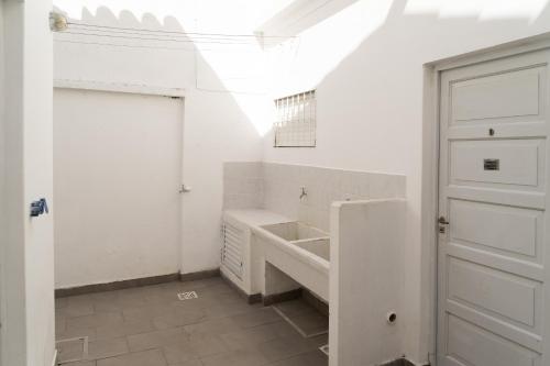 Baño blanco con puerta y lavabo en Departamentos BELVEDERE de Un Dormitorio y Monoambientes en San Clemente del Tuyú
