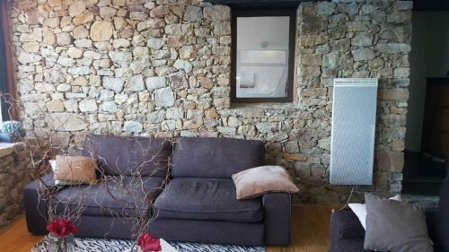 een woonkamer met een bank en een stenen muur bij La Gavaresse in Carqueiranne