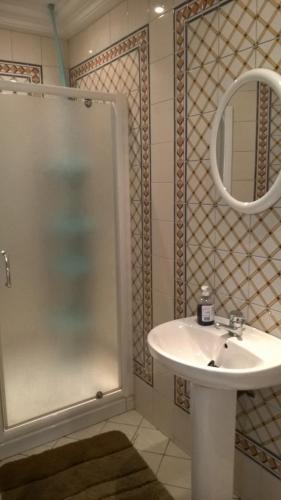 a bathroom with a sink and a shower with a mirror at Appartement Ain Zaghouan in Tunis
