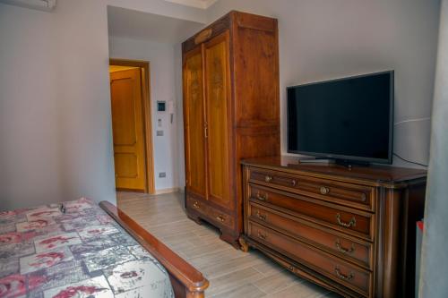 アルバにあるLe camere di Gioのベッドルーム1室(木製ドレッサー、ベッド1台、テレビ付)