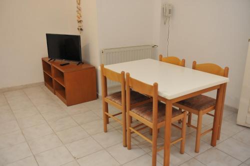 a dining room with a table and chairs and a tv at Niki Hotel Apartments in Ialyssos
